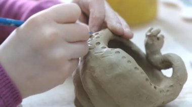 Çocuk seramik atölyede farklı türde kil ürünleri şekillendirmeyi öğreniyor. Çocuk, yaratıcı bir derste kilden bağımsız olarak çalışır..