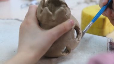 Çocuk seramik atölyede farklı türde kil ürünleri şekillendirmeyi öğreniyor. Çocuk, yaratıcı bir derste kilden bağımsız olarak çalışır..