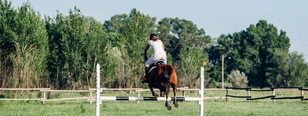 En kvinna jockey hoppar en barriär på en häst i sommar tävlingar. — Stockfoto