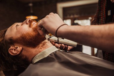 Profesyonel kuaför müşteri sakalı kesiyor.