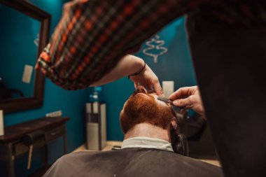 Profesyonel kuaför müşteri sakalı kesiyor.
