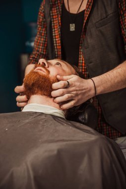 Profesyonel kuaför müşteri sakalı kesiyor.