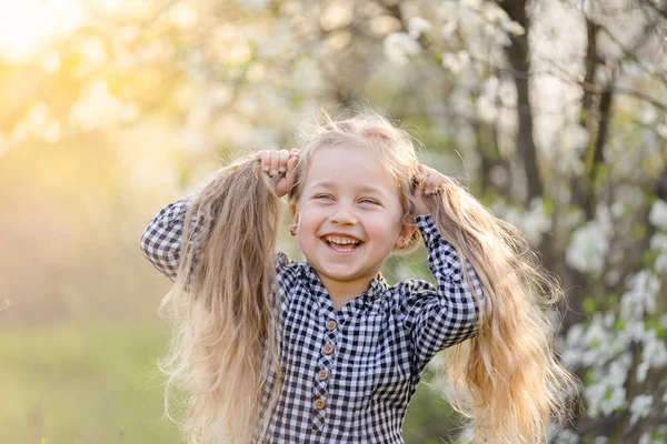 Piccola ragazza bionda che si diverte nel parco primaverile. — Foto Stock