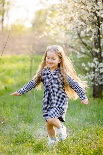 Piccola ragazza bionda che si diverte nel parco primaverile. — Foto Stock