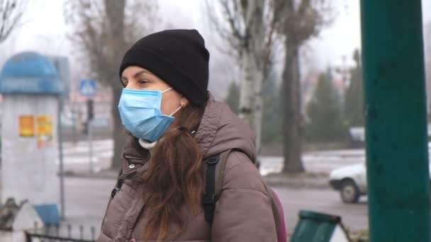 Μια νεαρή γυναίκα βγάζει μια σέλφι με μια προστατευτική ιατρική μάσκα στο δρόμο σε δημόσιο χώρο. Προστασία από τον κινεζικό κορωναϊό. — Αρχείο Βίντεο