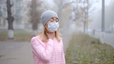 Coronavirus koruması. Tıbbi koruyucu maskeli genç bir kadın Avrupa 'da bir şehir caddesinde akıllı telefonuyla duruyor. Çin 'den gelen koronavirüsün belirtileri ortaya çıktı..