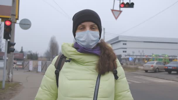 Schutz vor dem chinesischen Coronavirus in einer europäischen Stadt. Eine junge Frau steht in Deutschland auf einem öffentlichen Platz mit einer medizinischen Maske. Das Auftreten der Symptome des Coronavirus. — Stockvideo