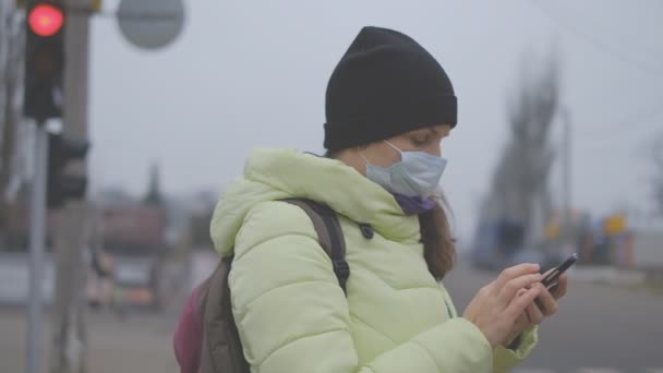 Ochrona Przed Koronawirusami Młoda Kobieta Medycznej Masce Ochronnej Stoi Smartfonem — Wideo stockowe