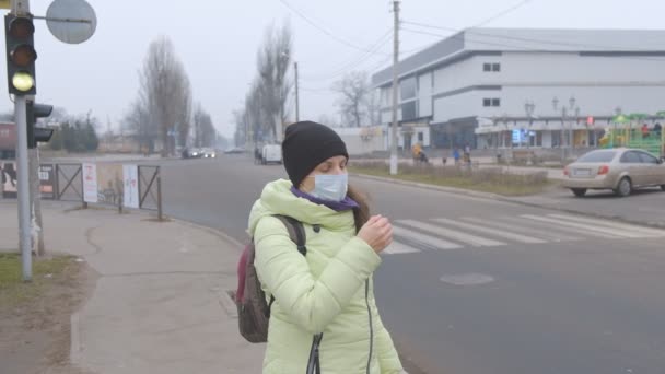 Schutz vor dem chinesischen Coronavirus in einer europäischen Stadt. Eine junge Frau steht in Deutschland auf einem öffentlichen Platz mit einer medizinischen Maske. Das Auftreten der Symptome des Coronavirus. — Stockvideo
