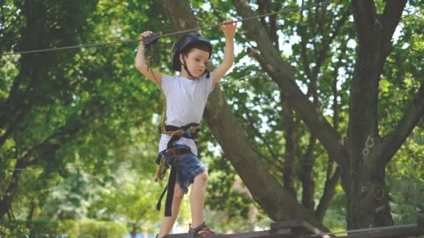 Un niño pequeño pasa por una atracción en un parque de cuerdas . — Vídeos de Stock