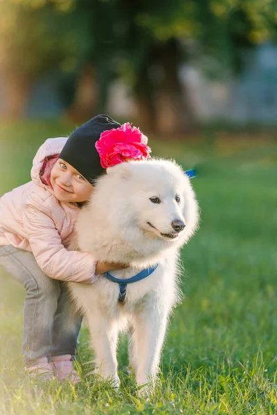 Petite fille promenades avec son chien Samoyed dans le parc — Photo