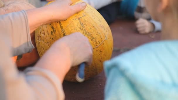 Preparándose para la fiesta de Halloween. Cortar una calabaza con un cuchillo. — Vídeos de Stock