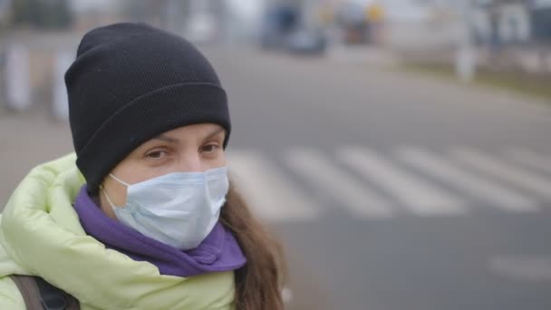 Bescherming tegen het Chinese coronavirus in een Europese stad. Een jonge vrouw op een openbare plaats staat met een medisch masker in Duitsland. Het ontstaan van symptomen van het coronavirus. — Stockvideo