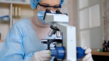 Koronavirüs üzerinde çalışan kadın bilim adamı. Doktor, koronavirüse karşı yapılan aşıyı mikroskopla inceliyor. Bir aşı oluşturuluyor.