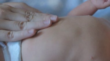 Bir kadın bebeğine karın masajı yapıyor. Kolik önleme.