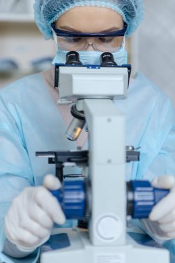 Koronavirüs üzerinde çalışan kadın bilim adamı. Doktor, koronavirüse karşı yapılan aşıyı mikroskopla inceliyor..