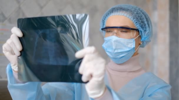 En læge kigger på en fluorografi scanning af en patient med coronavirus sygdom . – Stock-video