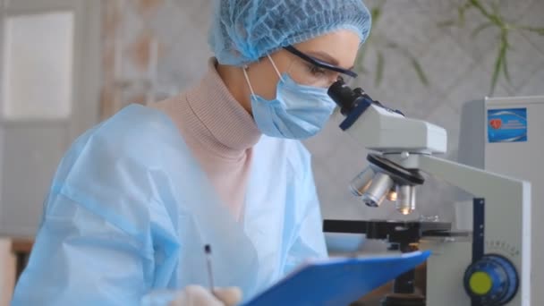 Egy női tudós tanulmányozza a koronavírust. Az orvos mikroszkóppal megvizsgálja a koronavírus elleni vakcinát.. — Stock videók