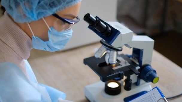 Ženská vědkyně studující koronavirus. Lékař se podívá mikroskopem na vakcínu proti koronaviru. — Stock video