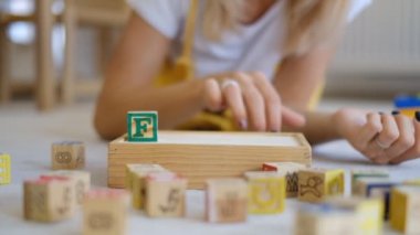 Kız küplerden sözcükleri topluyor. Kavramsal video. Tahta küplerden yapılmış harflerle yazılmış kelimeler..