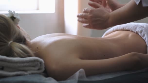 Un masajista hace un masaje de espalda profesional a una joven . — Vídeo de stock