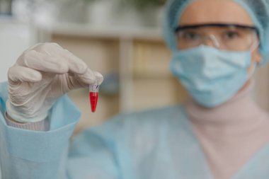 Bilim adamı doktor laboratuvarda koronavirüs Sars-Cov-2 'ye karşı bir aşı geliştirdi. Doktor elinde yeni bir aşı şişesi tutuyor..