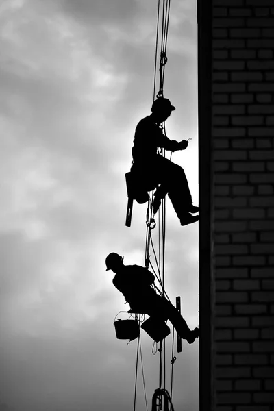 İki profesyonel adam dışarıdaki bir binayı izole ediyor. Endüstriyel yükseklik. İki dağcı evin duvarını iplerle yalıtıyor..