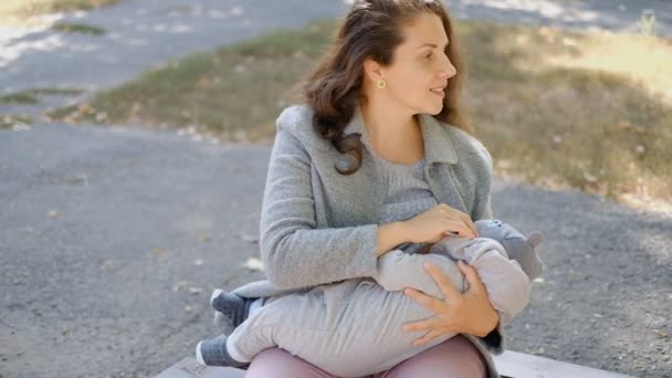 女性は夏の公園で赤ちゃんを屋外で母乳育児しています — ストック動画