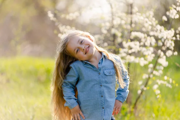 Little girl with beautiful thick hair has fun in the spring park.