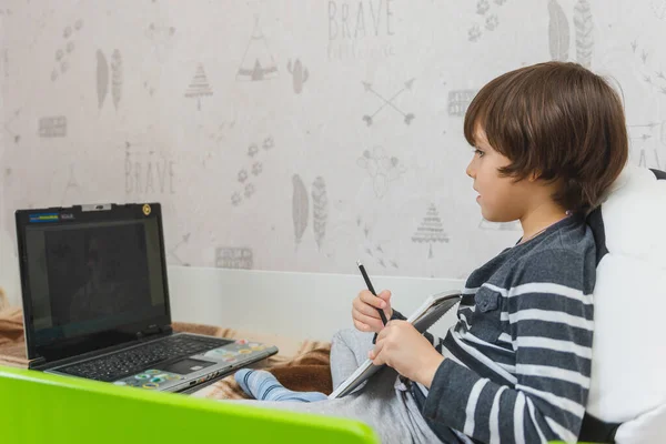 코로나 바이러스가 유행하는 아이들을 아이는 침대에 앉아서 인터넷 노트북을 사용하여 — 스톡 사진