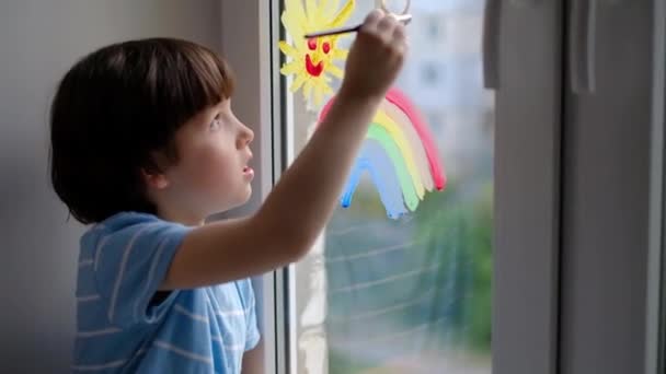 The pursuit of the rainbow. A little boy draws a rainbow on a quarantine window. Pandemic covid-19 . — Stock Video