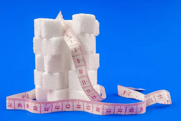 White sugar with measuring centimeter diet concept on blue background