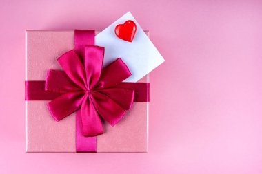 Pembe arka planda kırmızı kalpli Sevgi notuyla mevcut. Kopyalama uzayı.