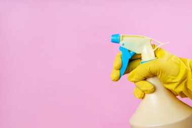 Pembe arka planda sprey bir şişeden eldivenli el spreyleri, kopyalama alanı, modelleme