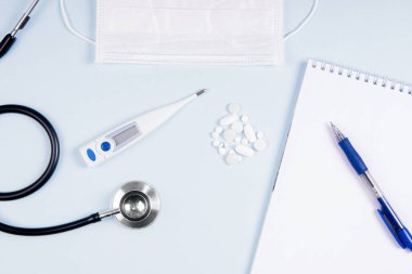 Steteskoplu, maskeli ve not defterli yassı doktor işyeri.