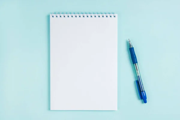 Düz dizüstü bilgisayar ve kalem mavi arkaplanda bir masanın üzerinde. Model