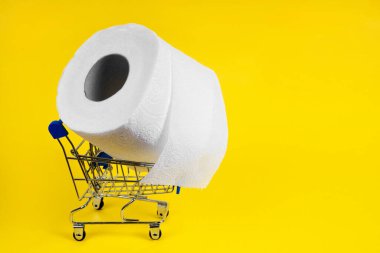 Tuvalet kağıdı yok. Sarı arka planda tuvalet kağıdı olan ürünler için alışveriş arabası. Market salgını olmaması kavramı Covid-19.