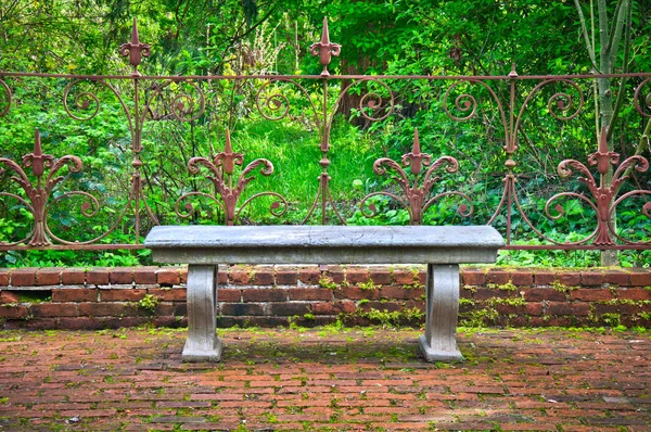 Παλιό πάγκο στο επίσημο αγγλικό κήπο με περίτεχνο σφυρήλατο σίδερο φράχτη — Φωτογραφία Αρχείου