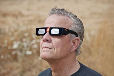 Man looking at the solar eclipse with eclipse glasses clipart