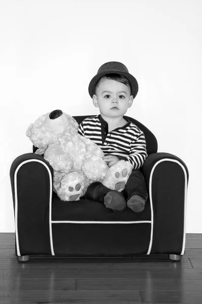 男孩佩带的帽子拿着泰迪熊在黑白摄影 — 图库照片