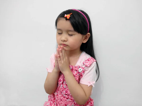 Sød lille asiatisk pige lukker øjnene og beder - Stock-foto