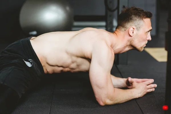 Człowiek robi rozciągające ćwiczenia na siłowni — Zdjęcie stockowe