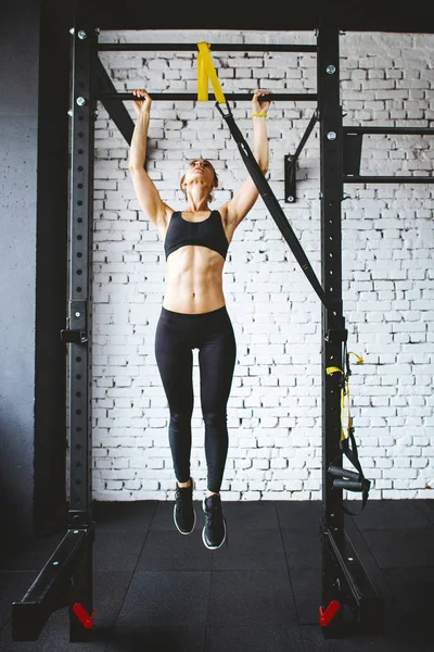 Młody fitness kobieta robi pull up w siłowni — Zdjęcie stockowe
