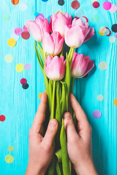 Bouquet av rosa tulipanblomster i menneskehender på blå trebakgrunn – stockfoto