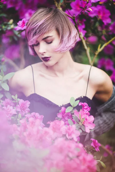 Mooie vrouw met roze haren in bloeiende lentetuin — Stockfoto