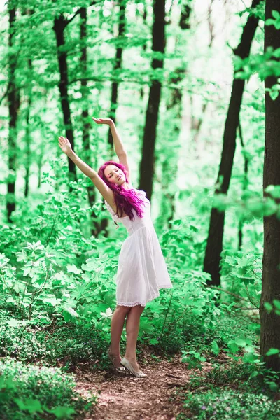 Jonge vrouw met roze haren in het bos — Stockfoto