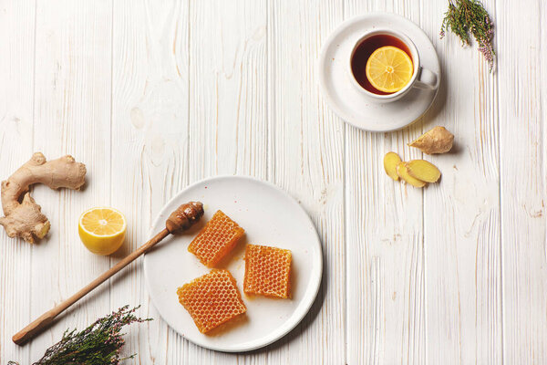 Плоские соты с ложкой меда, лимоном, имбирем и чашкой чая на деревянном фоне с копировальным пространством
.