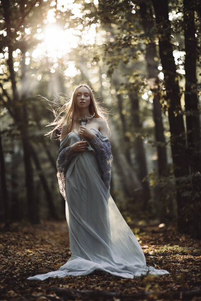 Fantasy portrait of fairytale beautiful woman in white dress in magic forest.