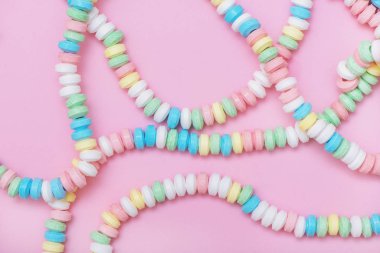 Pembe pastel renkli arka planda şeker kolye.