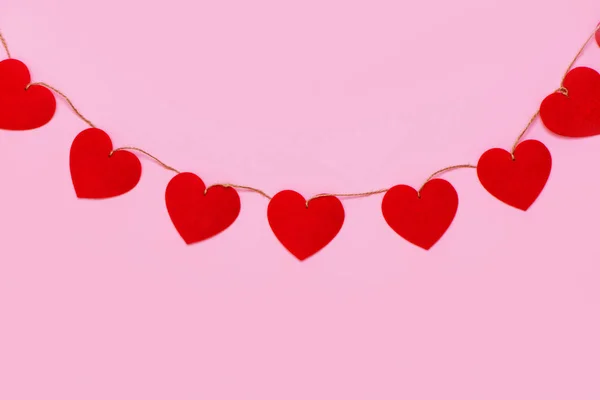 Hjärtan krans hängande på rosa bakgrund. — Stockfoto